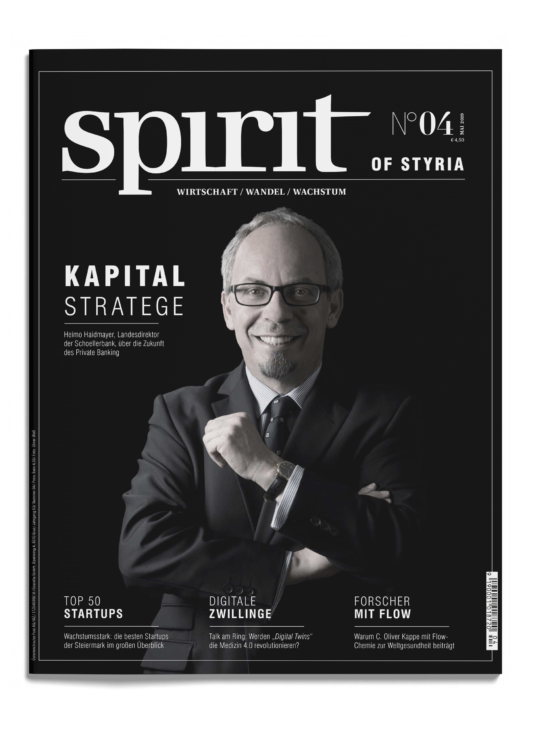 Das Titelbild einer Zeitschrift mit dem Titel "spirit of Styria" zeigt einen lächelnden Mann im Anzug und mit Brille, die Hand am Kinn, vor einem schwarzen Hintergrund.