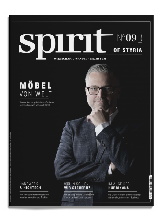 Das Titelbild eines Magazins mit dem Titel "spirit of Styria" zeigt einen Mann mit Brille und Anzug, der mit verschränkten Armen vor einem schlichten grauen Hintergrund steht.