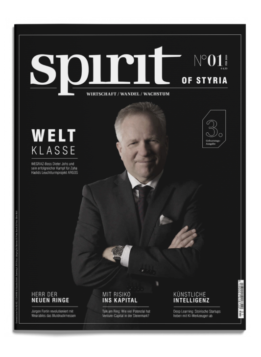 Ein Mann im Anzug steht selbstbewusst mit verschränkten Armen auf dem Cover des Magazins "spirit of styria", umgeben von deutschen Schlagzeilen auf schwarzem Hintergrund.