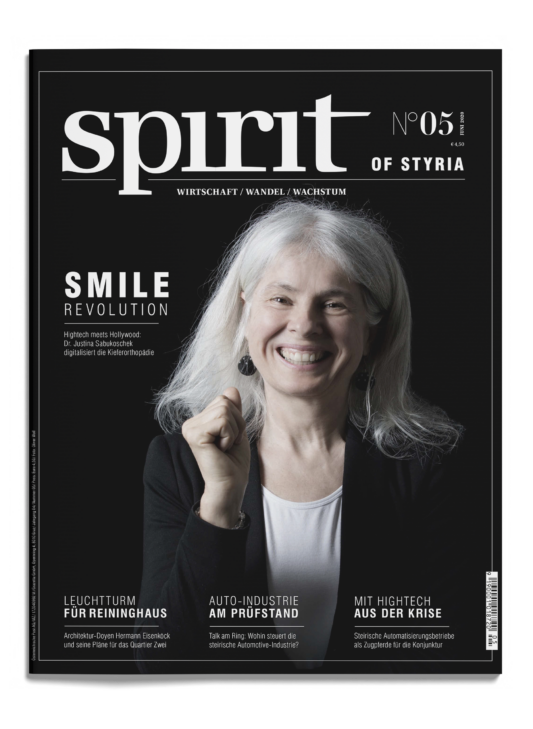 Eine lächelnde Frau mit langen weißen Haaren und einem schwarzen Blazer steht vor einem dunklen Hintergrund auf dem Cover des Magazins "Spirit of Styria", Ausgabe 05.