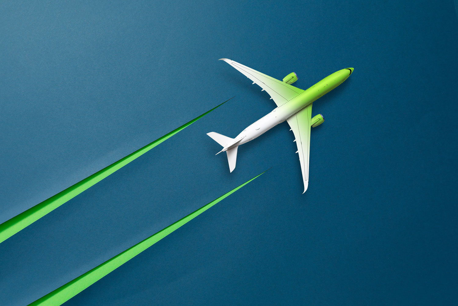 Ein grünes und weißes Flugzeug fliegt über einen blauen Hintergrund und hinterlässt zwei grüne Streifen, die Geschwindigkeit oder umweltfreundliches Fliegen symbolisieren.