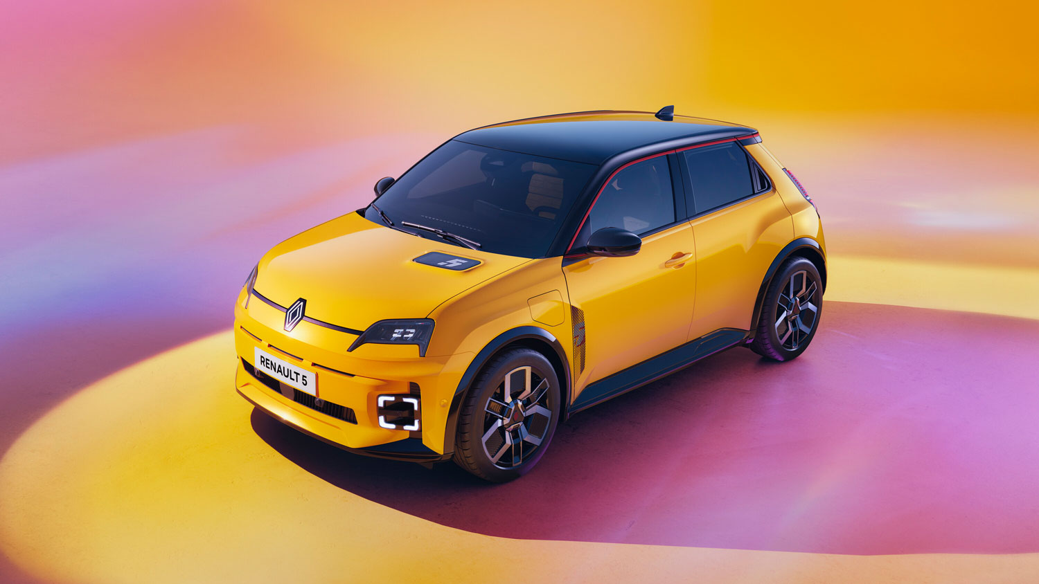 Ein leuchtend gelbes Elektroauto vom Typ Renault 5 ist auf einer glatten Fläche mit einem farbigen gelben und orangefarbenen Hintergrund geparkt, von vorne aus einem Dreiviertelwinkel betrachtet.