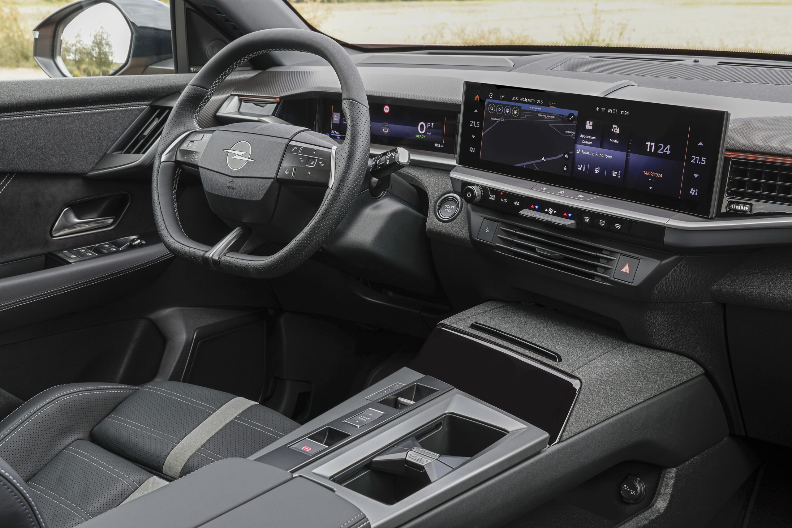 Modernes Fahrzeuginterieur mit digitalem Armaturenbrett, großen Infotainment-Bildschirmen, Multifunktionslenkrad und schwarzen Ledersitzen mit detaillierten Nähten. Die Mittelkonsole ist mit Getränkehaltern und verschiedenen Bedienelementen ausgestattet.