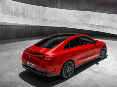 Ein schnittiges rotes Elektroauto ist in einer modernen, minimalistischen Betonstruktur geparkt, von hinten aus einer Dreiviertelperspektive betrachtet. Das Auto verfügt über getönte Scheiben, schwarze Räder und ein elegantes, aerodynamisches Design.