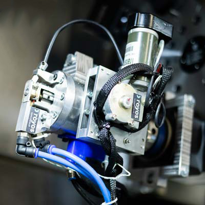 Nahaufnahme einer Industriemaschine mit Metallteilen, Drähten, blauen Schläuchen und einem SOKOL-Etikett, die komplizierte technische und elektrische Teile miteinander verbindet.