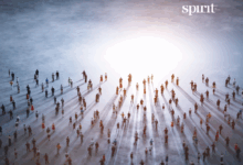 Eine große Gruppe kleiner, silhouettierter Menschen steht mit Abstand auf einer nebligen Fläche und wirft lange Schatten in Richtung eines hellen Lichts in der Ferne. Das Wort "Geist" erscheint in der oberen rechten Ecke.