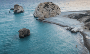 Luftaufnahme einer felsigen Küste mit türkisfarbenem Wasser, großen Felsformationen im Meer und einem schmalen Strand bei Sonnenuntergang. Das Wort "Geist" erscheint in der unteren rechten Ecke.