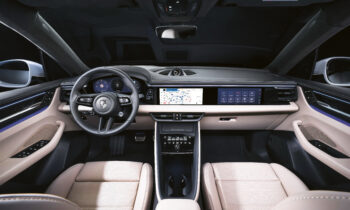Ein moderner Innenraum mit beigen Ledersitzen, einem digitalen Armaturenbrett, einem großen Touchscreen-Display mit Kartendarstellung und einem sportlichen Lenkrad mit Porsche-Logo. Der Innenraum hat ein schlankes, hochtechnisches Design.