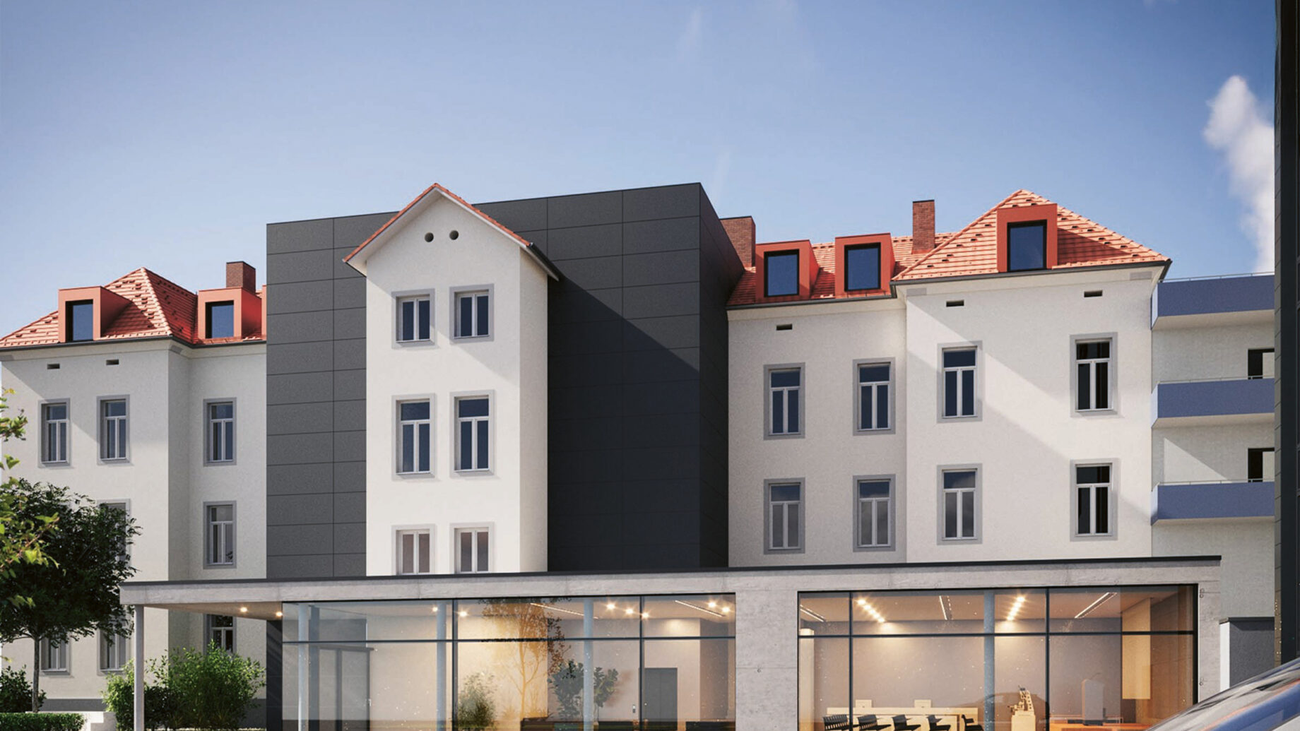 Ein modernisiertes weißes Gebäude mit roten Dachziegeln und großen schwarz getäfelten Abschnitten, mit einem verglasten Erdgeschoss mit sichtbaren Sitzbereichen, unter einem klaren blauen Himmel. Rechts unten ist die Frontpartie eines Autos zu sehen.