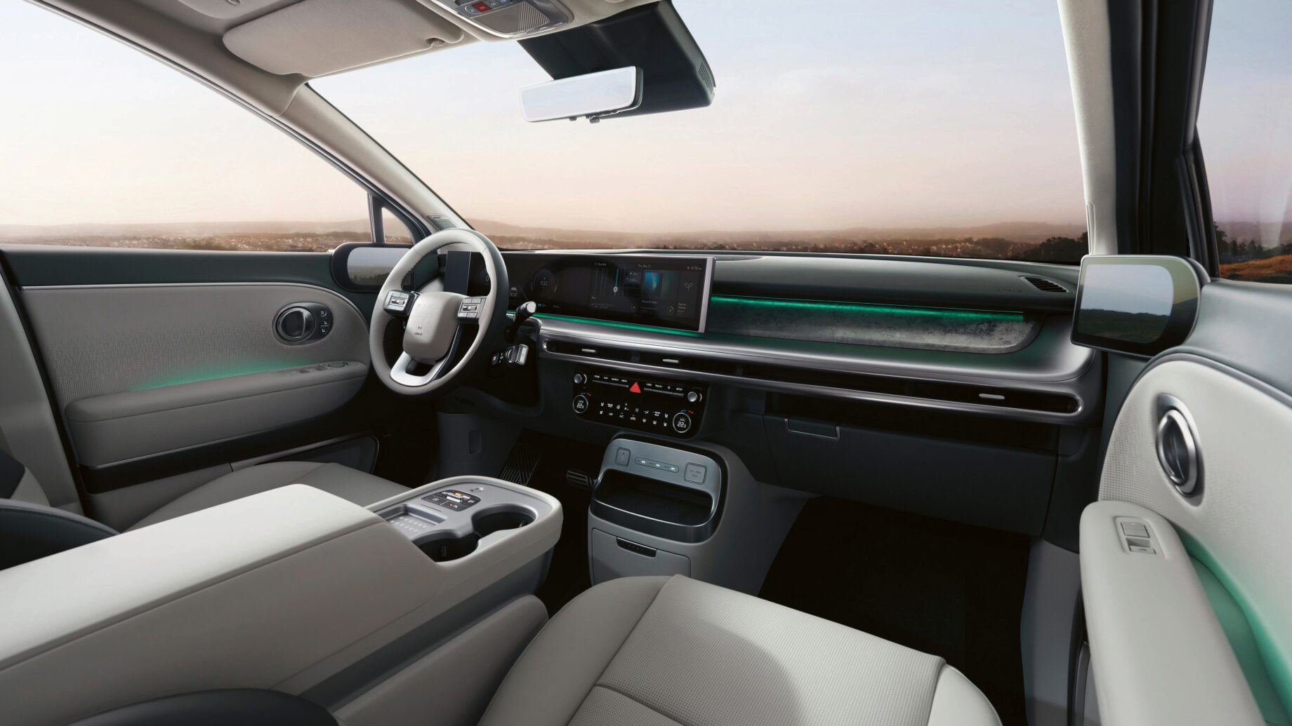 Modernes Interieur mit hellgrauen Sitzen, digitalem Armaturenbrett, Touchscreen-Displays und grünen Lichtakzenten. Die große Windschutzscheibe bietet einen malerischen Blick auf die Landschaft.