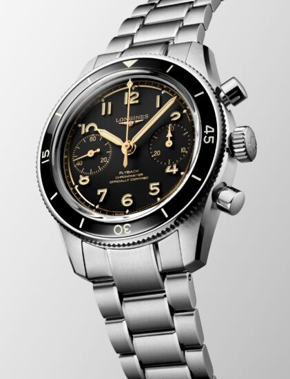 Nahaufnahme einer Longines-Armbanduhr aus Edelstahl mit schwarzem Zifferblatt, goldenen Ziffern und Chronographen-Zwischenziffern, einem Metallgliederarmband und einer schwarzen Lünette mit weißen Markierungen.