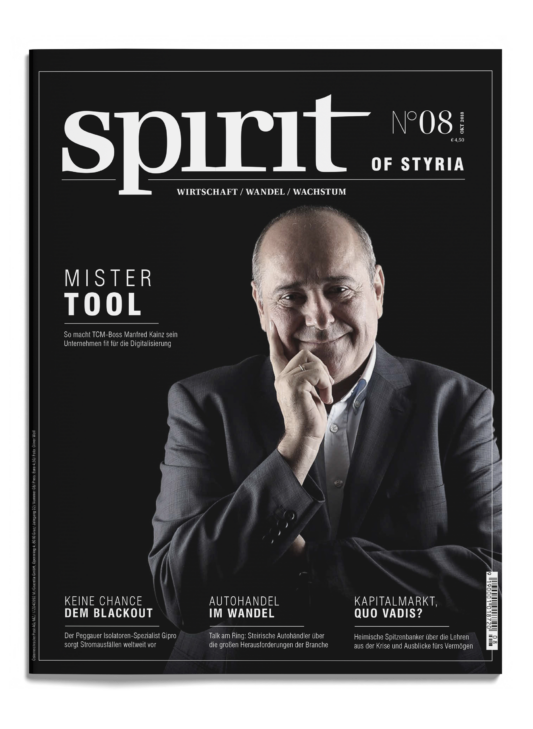Ein lächelnder Mann im Anzug hält seine Hand an sein Kinn auf dem Cover des Magazins "spirit of styria", Ausgabe 08. Um ihn herum erscheinen weiße Textüberschriften.