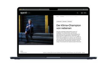 Auf einem Laptop erscheint ein deutscher Online-Artikel mit dem Titel "Der Klima-Champion von nebenan", in dem ein Mann im Anzug vor gestapelten Metallrohren sitzt.
