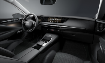 Modernes Interieur mit schwarzen Sitzen, digitalem Armaturenbrett, Touchscreen-Display und minimalistischem Design mit Metall- und Kohlefaserakzenten.