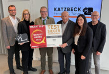 Sechs Personen stehen lächelnd mit Auszeichnungen, zwei halten Urkunden für Qualität und Kundentreue - ein wenig Licht für jene, vor dem Katzbeck-Logo.