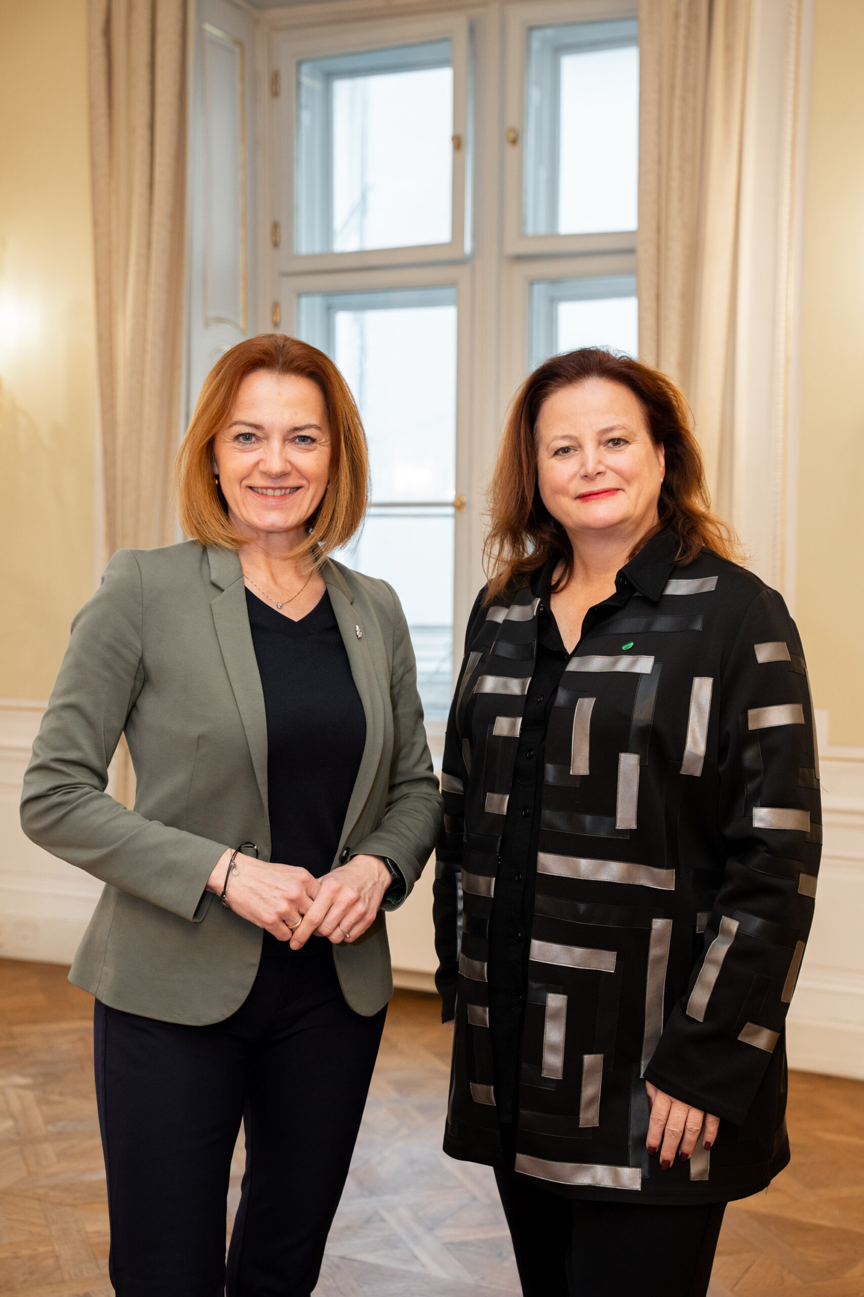 Zwei Frauen stehen Seite an Seite in einem hellen Raum, als Emerald Horizon Robert Holzmann zum Vizepräsidenten ernennt. Beide lächeln in die Kamera.