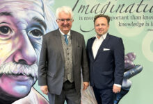 Zwei Männer in Anzügen stehen vor einem Wandbild von Einstein, als die Energie Steiermark startet Bau Logistikzentrum in Frohnleiten mit Phantasie und Wissen inspiriert.