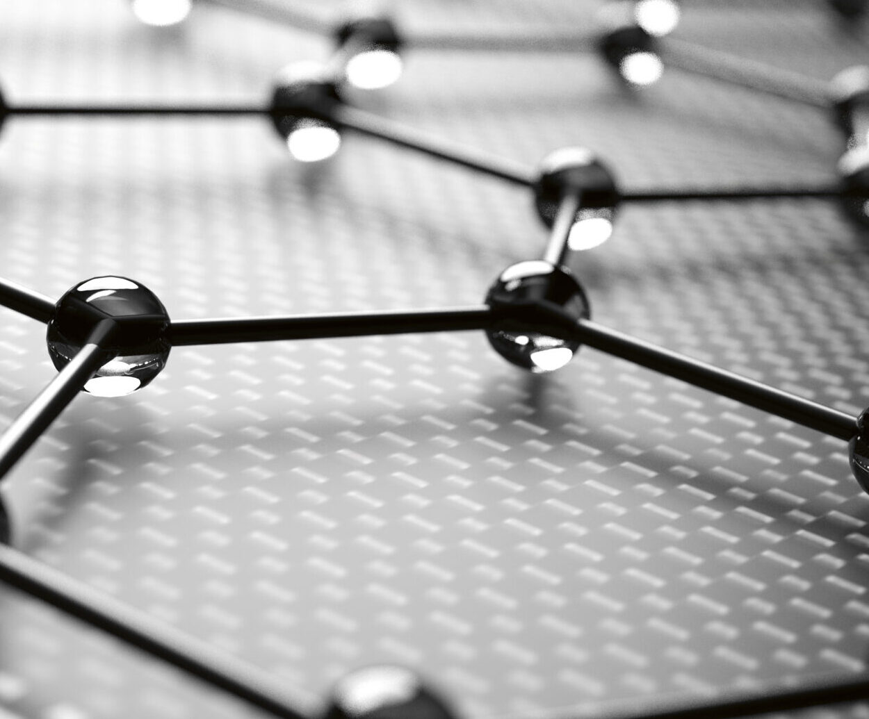 Nahaufnahme einer Graphenplatte, die eine sechseckige Gitterstruktur mit miteinander verbundenen Atomen zeigt, dargestellt in Schwarz-Weiß.