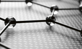 Nahaufnahme einer Graphenplatte, die eine sechseckige Gitterstruktur mit miteinander verbundenen Atomen zeigt, dargestellt in Schwarz-Weiß.