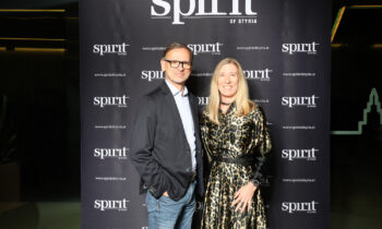 Ein Mann und eine Frau posieren gemeinsam lächelnd vor einer "Spirit of Styria"-Kulisse bei einer Veranstaltung.