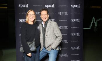 Zwei Personen lächeln und posieren gemeinsam vor einem schwarzen Step-and-Repeat-Hintergrund mit "spirit of Styria"-Logos.