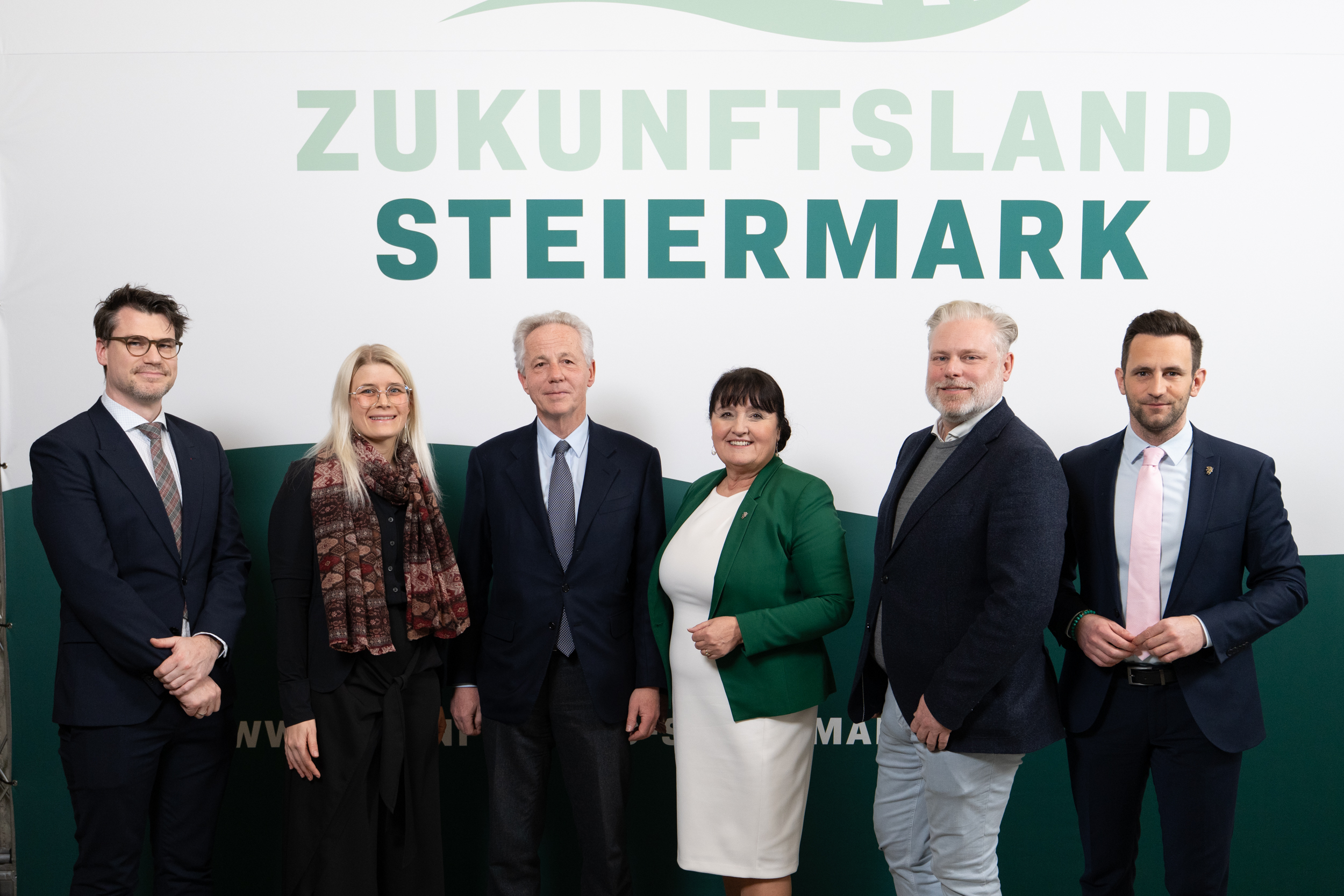 Sechs Fachleute posieren vor einem Schild "Zukunftsland Steiermark", das die klare Mehrheit für soziale Sicherheit in der Steiermark widerspiegelt.