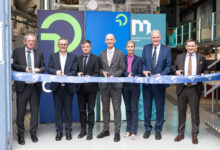 Sieben Personen in Geschäftskleidung durchschneiden bei der Zeremonie im Haus der Stillen Sanierung 2026 ein blaues Band, im Hintergrund sind Transparente zu sehen.