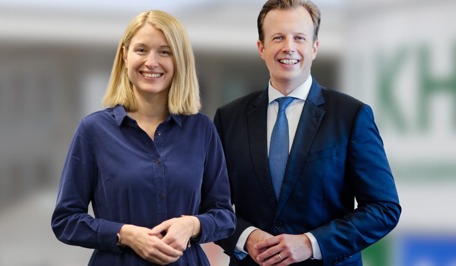 Zwei Personen lächeln nebeneinander bei 30 Jahre FH CAMPUS 02: Wo aus Wissen Können wird; die eine in einem blauen Kleid, die andere in einem dunklen Anzug mit blauer Krawatte.