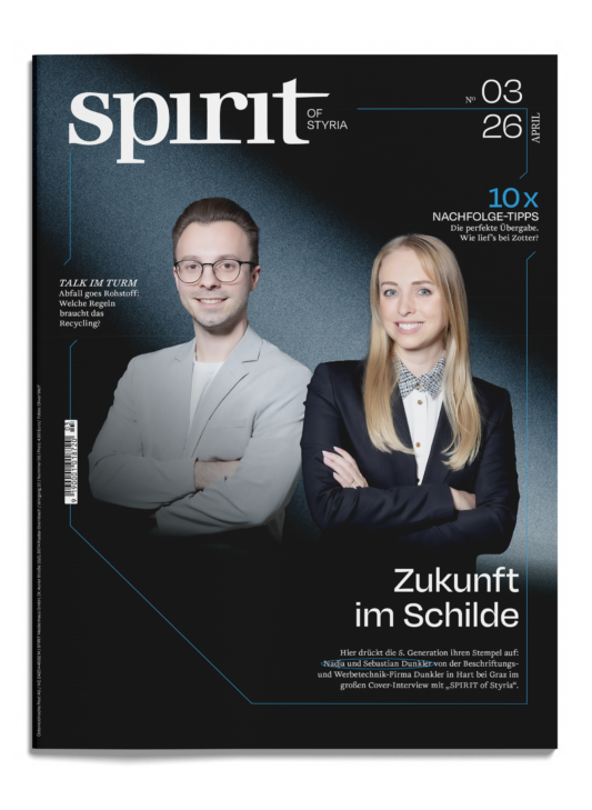 Ein Mann und eine Frau in Business-Kleidung stehen lächelnd auf dem Cover des Magazins "spirit of Styria", Ausgabe 03/26. Die Überschrift lautet "Zukunft im Schilde.