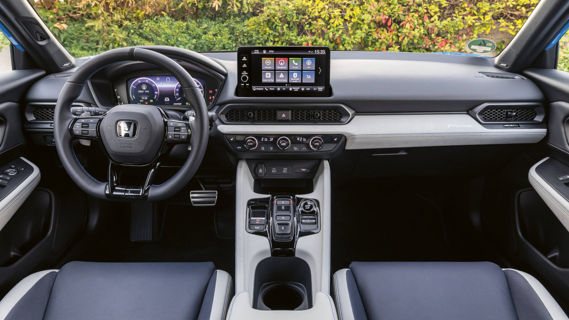 Modernes Autointerieur mit digitalem Armaturenbrett, Touchscreen-Display und schwarz-weißen Sitzen mit sichtbarer Mittelkonsole und Lenkrad.