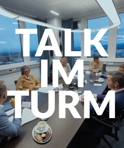 Sechs Personen in Business-Kleidung treffen sich in einem modernen Büro. Der große Text lautet: "TALK IM TURM".