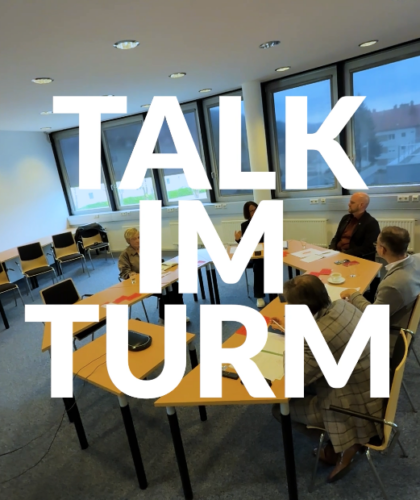 Fünf Personen treffen sich in einem hellen Raum; fett gedruckt steht "TALK IM TURM.