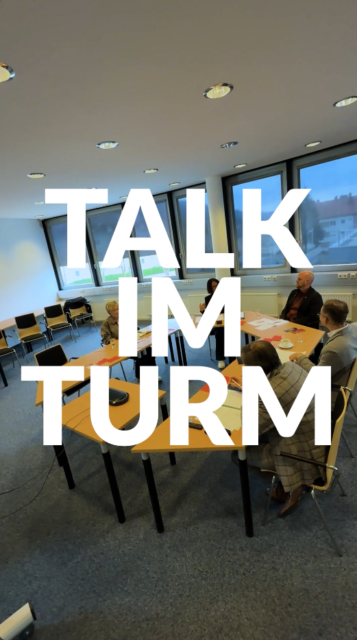 Fünf Personen treffen sich in einem hellen Raum; fett gedruckt steht "TALK IM TURM.