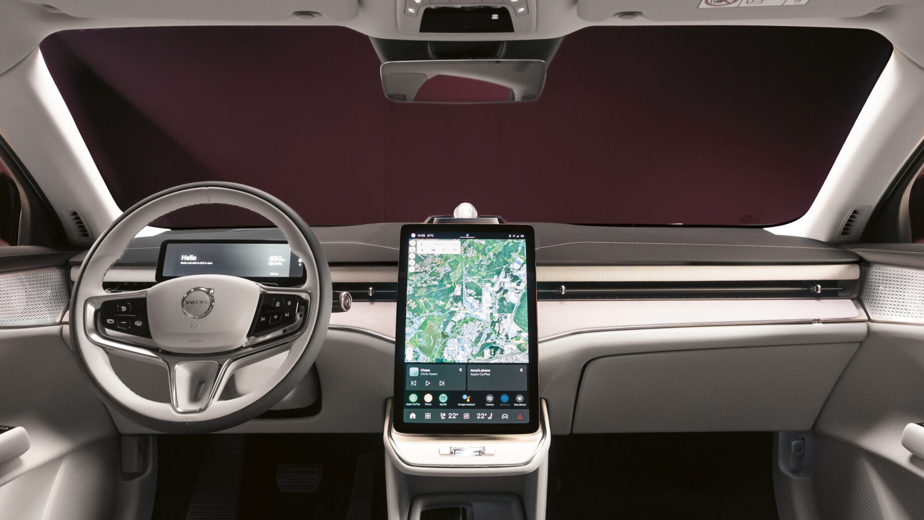 Modernes Fahrzeuginterieur mit digitalem Armaturenbrett, großem zentralen Touchscreen mit Kartendarstellung und Volvo-Logo am Lenkrad.