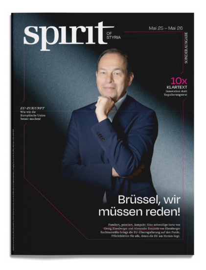 Auf dem Titelblatt des Magazins „Spirit of Styria“ – mit deutschem Text und dunklem Hintergrund – steht ein Mann im Anzug selbstbewusst da und stützt die Hand am Kinn.