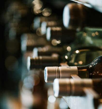 Nahaufnahme von verschiedenen Weinflaschen, die auf der Seite auf einem Weinregal liegen, mit geringer Schärfentiefe und weicher Beleuchtung.