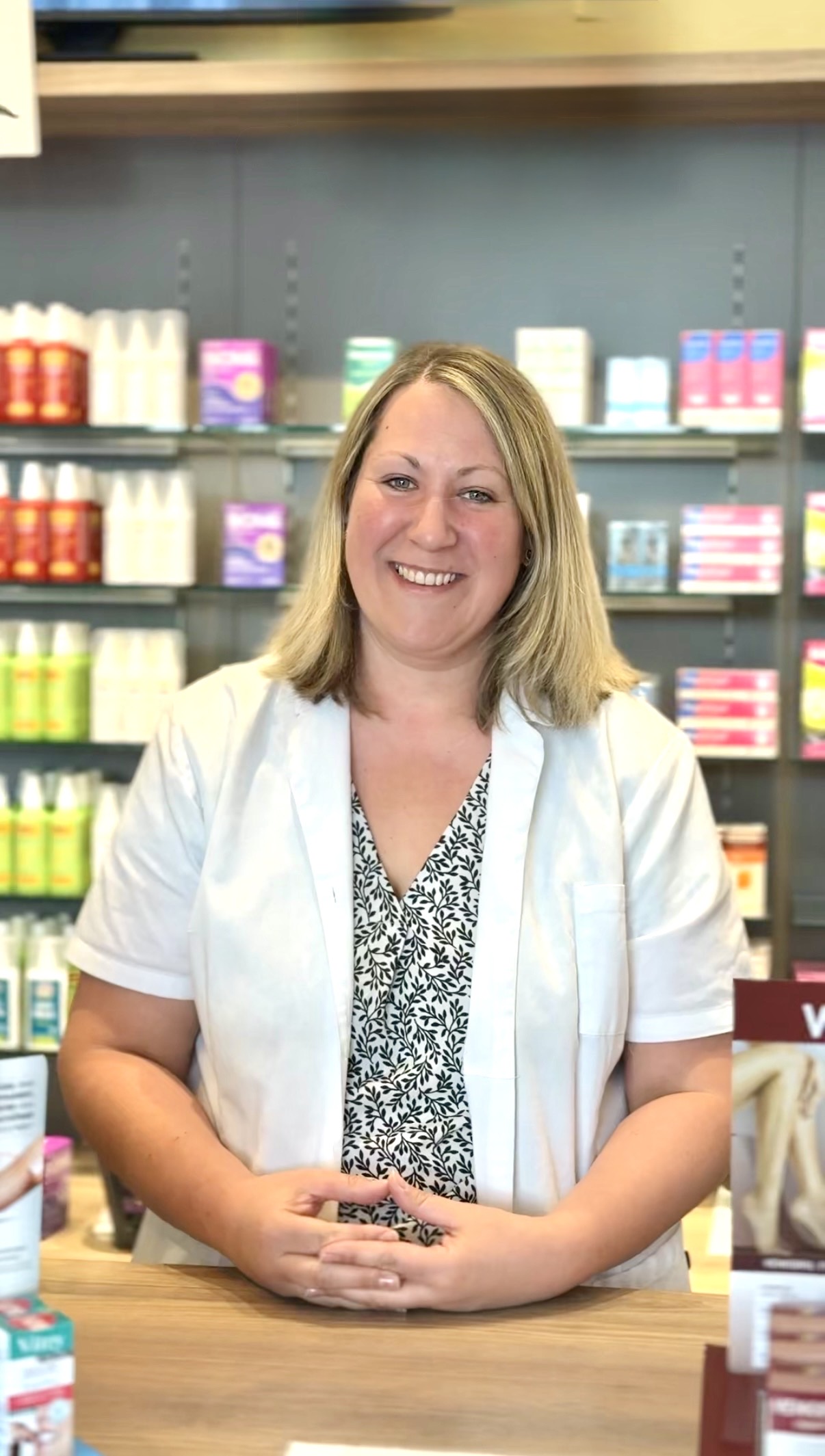 Christine Gradwohl aus Graz lächelt im weißen Kittel hinter dem Tresen - Apotheken-Stars gesucht!
