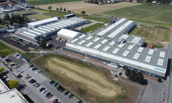 Luftaufnahme eines großen Siemens-Werks anlässlich des Jubiläums „125 Jahre Siemens in der Steiermark“, umgeben von Parkplätzen, Feldern und Straßen.
