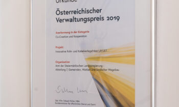 Ein gerahmtes Zertifikat für den Österreichischen Verwaltungspreis 2019, mit dem ein Projekt in der Kategorie „Mitgestaltung und Zusammenarbeit“ ausgezeichnet wurde, hängt an einer Wand.