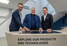 Christopher Hermann, Michael Mertin und Georg Knill stehen in der neuen AT&S-Erlebniswelt in Fehring an einem interaktiven Ausstellungstisch.
