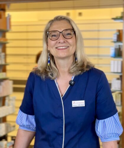 Ilse Gruber aus Köflach: Eine Kandidatin beim "ApothekenStar 2026-Voting" steht lächelnd in ihrem blauen Kittel in ihrer gut sortierten Apotheke.