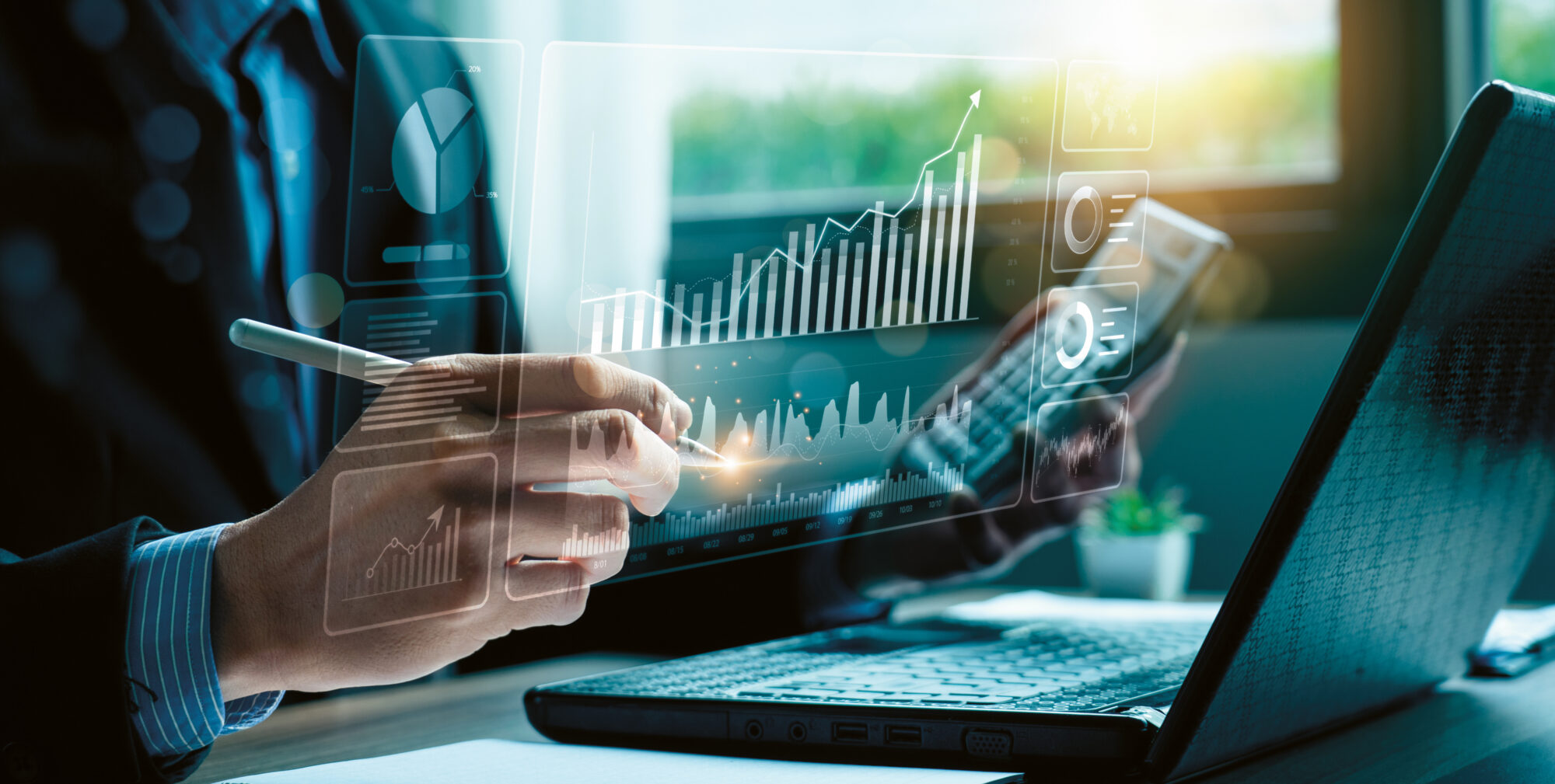 Eine Person, die auf einem Laptop mit einem Stylus virtuelle Finanzdiagramme analysiert, umgeben von Charts und Sonnenlicht, das durch ein Fenster fällt.