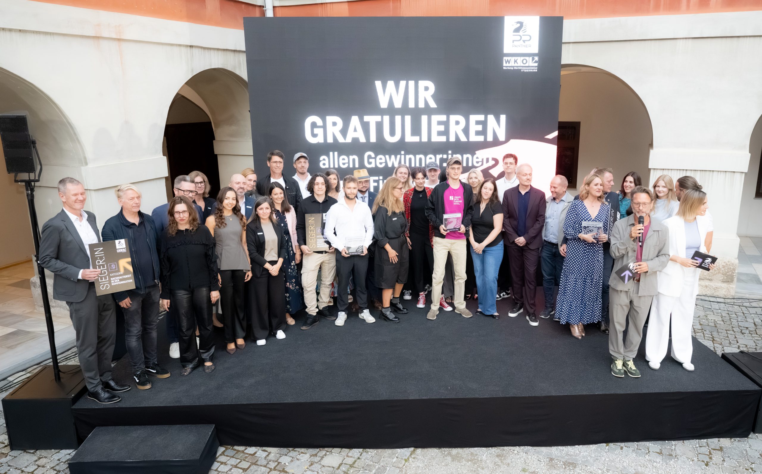 Eine Gruppe posiert auf der Bühne der EBSCON 2026 vor einem Schild mit der Aufschrift „WIR GRATULIEREN“ während einer Preisverleihung.