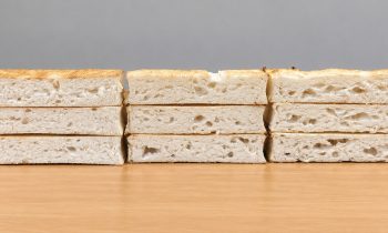 Drei Stapel geschnittenes Weißbrot, auf einer Holzunterlage angeordnet.