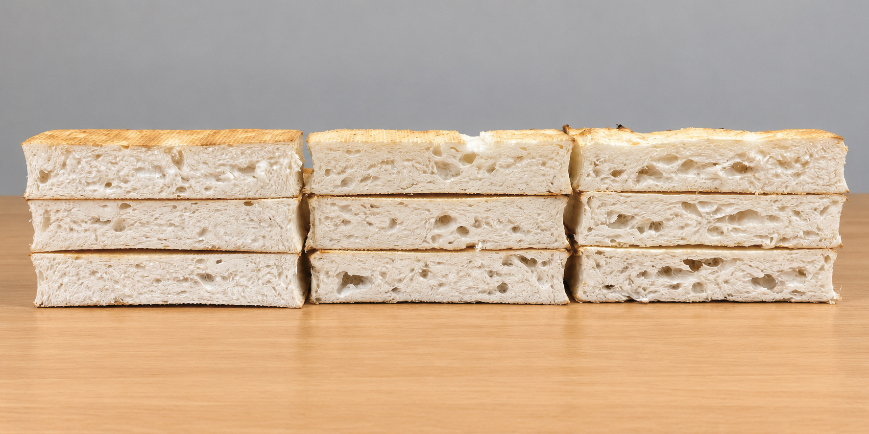 Drei Stapel geschnittenes Weißbrot, auf einer Holzunterlage angeordnet.