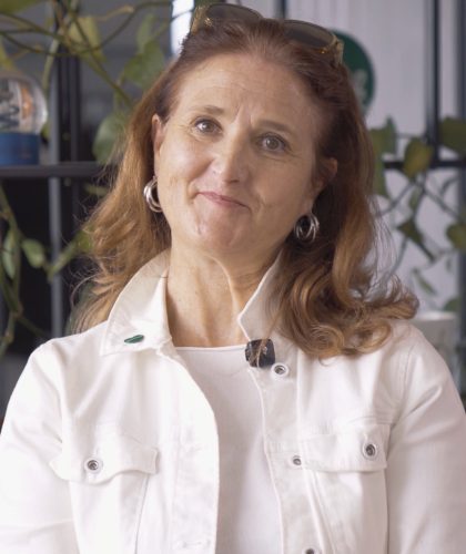 Susanne Haubenhofer mit rotbraunen Haaren und einer weißen Jacke lächelt in die Kamera.