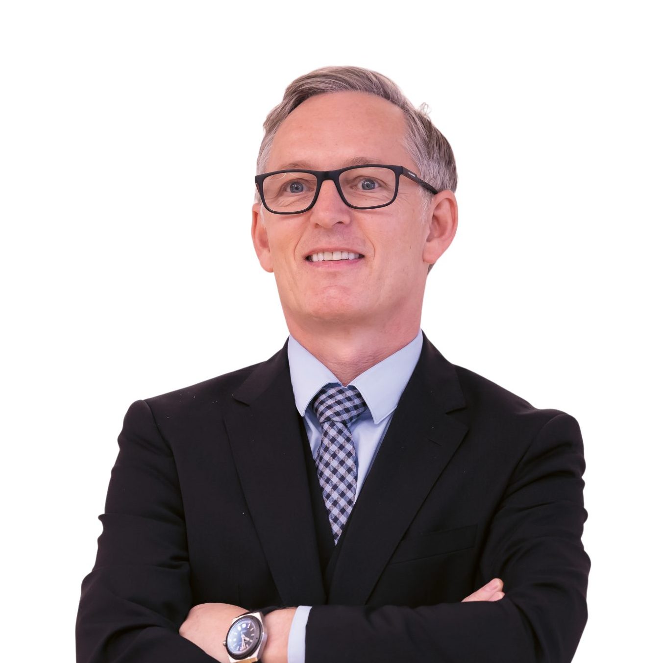 Ein Mann im Anzug und mit Brille steht da, die Arme verschränkt.