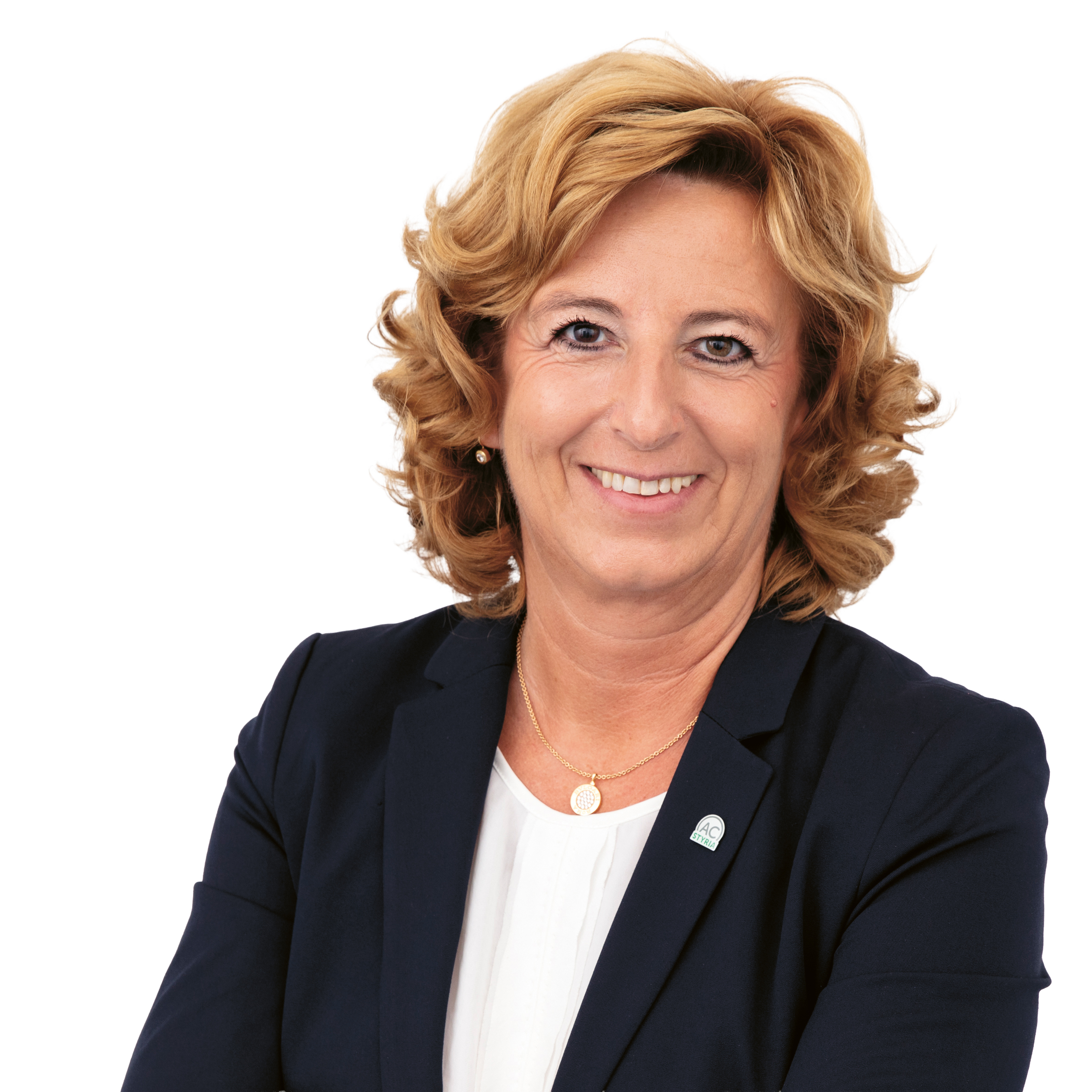 Eine Frau mittleren Alters mit schulterlangen blonden Haaren, die einen marineblauen Blazer über einer weißen Bluse trägt.